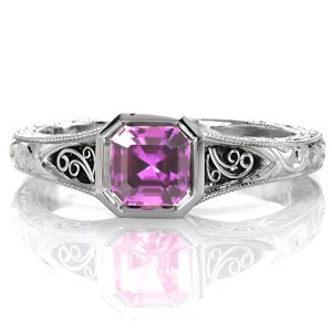 This remarkable, antique inspired design features a .90 carat asscher cut purple sapphire. A high polished bezel outlines the shape of colorful octagon center stone. The sides and top of the band reveal hand carved relief scroll engraving and platinum hand formed filigree. 