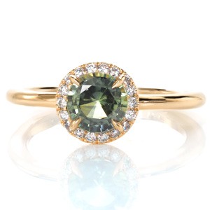 Yellow gold halo sapphire engagement ring in Chicago. Diamond details beautifully frame a stunning green sapphire. 