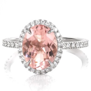 Micro pavé diamonds outline the shape of the 2.00 carat oval gemstone. The brilliance of the diamonds enhance the beauty of the soft pink hue of the morganite center. Throughout the setting, hand crafted u-cut prongs allow more light to reach the surface of diamonds for added shine and radiance. 