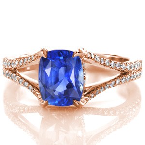 A breathtaking statement, Design 2472 places focus on the 2.00 carat cushion cut blue sapphire center gemstone.  The decorated split shank band is detailed with individually hand-set  micro pavé. Diamonds also decorate the basket, adding more sparkle to the profile view. 