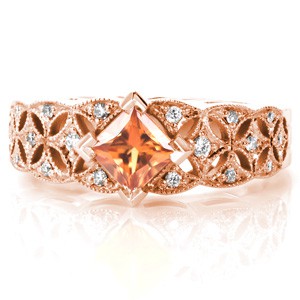 Orange sapphire engagement ring in rose gold in Portland. Rose gold engagement ring featuring a kite-set princess cut sapphire. The antique band style features an openwork starburst pattern set with diamonds.