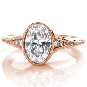 An exquisite design, the Oval Marseille features a bezel set, 1.50 carat oval cut diamond on a knife edge band. The band has three stones on each side of the center and then tapers into a double milgrain edge. The sides of the band are hand engraved and the basket has filigree and surprise diamonds.