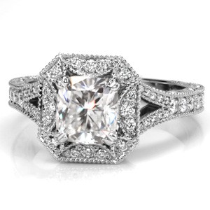This regal design features a cushion cut center stone surrounded by a unique rectangular halo with clipped corners. The split shank band is adorned with diamonds and milgrain and draws the eye to the magnificent halo. Relief engraving and filigree are created by hand giving Design 3499 an antique appeal.   