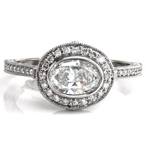  Design 3502 is a stunning halo engagement ring with a damask inspired pattern in the basket. Hand carved, relief style scroll engraving compliments the damask pattern. Micro pavé diamonds are set in the halo and on top of the band. The horizontally set oval center stone is elegantly secured with a bezel setting. 