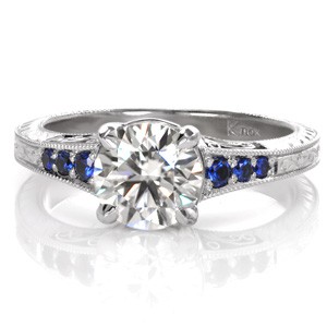 Design 3503 captures the rich cobalt blues within its round graduating sapphires. Vintage-inspired details of milgain, filigree, and hand engraving adorn the sides of the band. A 1.20 carat round brilliant center stone is fashioned within the 14k White Gold setting for added radiance and shine.