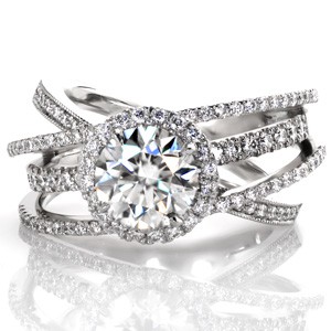 Design 3507 is an extraordinary custom engagement ring combining one of our signature wide bands with a glittering diamond halo. Four diamond bands, differing in settings styles, frame the center 1.50 carat round brilliant diamond held in its halo. Colored surprise stones add the final touch to this custom design!