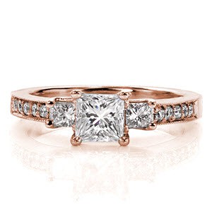 Royal Princess Three Stone is a classic design with a contemporary twist. The 0.50 carat princess cut is flanked on each side by similar square shaped stones. The band is accented with five bead-set round brilliant diamonds and milgrain texture to enhance the beauty of the three stone design. 