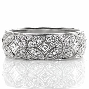 Design 3516 conveys elegance with its curving lines and intricate interlocking pattern. This wide, half-round band features bezel set carre cut diamonds surrounded by mosaic-like sections of bead set side diamonds. Milgrain edging adds the final vintage inspired touch to this exquisite custom ring. 