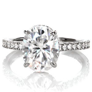 Design 3523 is a custom engagement ring of elevated elegance. A contemporary silhouette is finished with micro pavé diamonds placed into delicate u-cut settings. The dazzling oval moissanite center stone is cradled by a bejeweled four prong basket. This design is a streamline setting with extraordinary details.