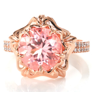 A stunning 3 carat round cut rosy morganite is featured in Design 3525. The exceptional center stone is surrounded by a distinctive floral shaped halo. It includes a double layer of high polished petals and five claw prongs that blend seamlessly into the design. A double row of micro pavé diamonds adorns the band.