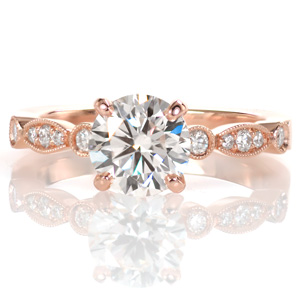 Design 3526 is an elegant update to a classic solitaire setting. The band's scalloped outline and differing stone settings make it a unique addition to a timeline ring design. At the center, a four prong basket holds a glittering 1.00 carat round diamond and milgrain edging adds a vintage inspired finishing touch.