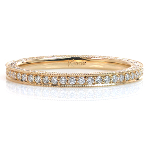 Featuring small round brilliant cut diamonds, this custom eternity style wedding band is a dazzling addition to any wedding set. The beadset style of the diamonds is complimented by the milgrain texture on the edges of the piece. One side of the band is kept high polished to face the engagement ring.