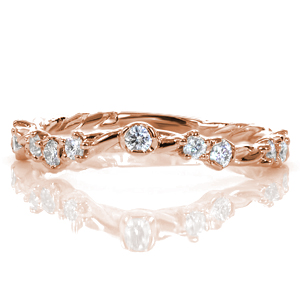 An organic custom wedding band created to subtly contour around an engagement ring, Design 3546 features a twisted vine style band. Small round brilliant cut diamonds are set in a mixture of prong and semi-bezel styles to mimic clusters of delicate flowers.  