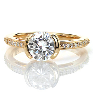 This elegant contemporary design features a half bezel center setting that reveals the full profile of the center stone from the side. The delicate band is set with small round brilliant diamonds, and features open pockets that could be filled with hand wrought filigree curls for an added vintage appeal.