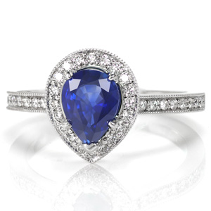 Alluring with a lush blue sapphire center stone, Design 3564 is shown with a pear shaped micro pavé halo. The diamond apron around the sides of the halo and the cathedral style band are also adorned with micro pavé diamonds. This engagement ring is designed to easily sit flush with a wedding band.