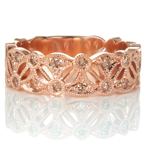 Champagne diamonds perfectly compliment the rich warm hues of rose gold in this wide band design. Round stones are set into an alternating arrangement of round bezel settings and flared fans for an Art Deco inspired pattern. Beaded milgrain texture adorns the edges, adding to the antique appeal.