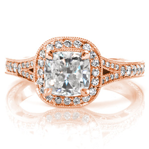 Classic antique details are brought to life in exquisite beauty with this split-shank halo engagement ring. The center is shown as a cushion cut diamond surrounded by a micro pavé double sided halo. The band is additionally adorned with delicate hand engraving, hand wrought filigree curls, and milgrain detail. 