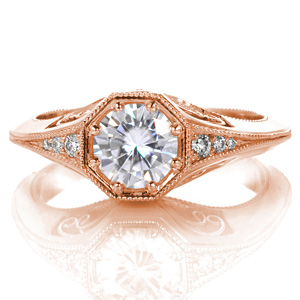 Elegantly crafted, this ring features a knife-edge band with an octagonal center setting. The flared band perfectly flows into the under-bezel basket allowing for small bead-set diamonds on the top. Open pockets in the basket feature delicate hand wrought filigree curls. Milgrain adds texture to the edges of the piece.