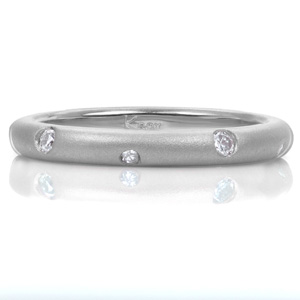 Sparkling like stars, small flush set diamonds alternate in size as they dance around this contemporary band. The contrast between the dazzling gems and the luster of the matte sandblasted finish highlights the complimentary pairing with a feeling of modern elegance.