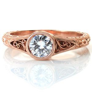 Design 3612 is all about scroll-work and smooth, rounded curves. Shown with a band that flares to meet to the sides of the center bezel setting, there are pockets on all three sides featuring hand wrought filigree curls. Below the filigree, the ring is relief engraved with a hand-stippled background. 
