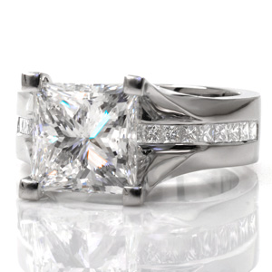 Featuring a wider band with a channel set row of princess cut diamonds running completely under the center stone, Design 3619 is a contemporary masterpiece. The raised four prong center setting creates a cathedral style perfect for the princess cut center stone currently featured in the piece.