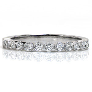 Small round brilliant diamonds in delicate bezel settings form the upper half of this beautiful band. The upper edge of each bezel is lovingly hand detailed with a beaded milgrain texture for added vintage appeal. This diamond band is perfect for stacking or wearing alone.