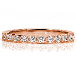 Small round brilliant diamonds in delicate bezel settings form the upper half of this beautiful band. The upper edge of each bezel is lovingly hand detailed with a beaded milgrain texture for added vintage appeal. This diamond band is perfect for stacking or wearing alone.