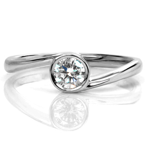 A beautiful bezel set solitaire, Design 3626 is a contemporary piece with a wrapping band. The band tapers in as it approaches the center stone, placing all focus on the dazzling round brilliant center stone. This modern twist on a classic style creates a fantastic solitaire option.