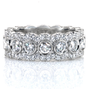 Design 3629 is a lavish eternity span diamond band. The mixed setting styles and varied stone sizes create a  pattern of overlapping halos around larger bezel set interior gems. The scalloped diamond rails that form the partial halos are held in U-cut style prong settings.