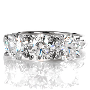 This breath-taking three stone ring features three individual 1.00 carat round brilliant cut diamonds. The high polished band is a little wider to accent the sparkle of the stones with the luster of the high polished metal. A woven, trellis style setting forms a decorative basket on the sides of the piece.