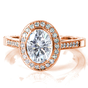The magnificent 1.20 carat oval is framed in a high polish bezel then surrounded by micro pavé diamonds and a milgrain border.  The sides of the band are adorned with scroll hand engraving, filigree, and diamonds for a majestic profile. Round diamonds line the top of the ring to enhance the shimmer of the band.