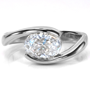An oval set East-West adds a contemporary flair to a classic design. The elongated shape of the oval fills the open space along the top of the band perfectly. The high polish finish creates a sleek transition for the eye to focus upon the flashes of brilliance projecting from the center stone. 
