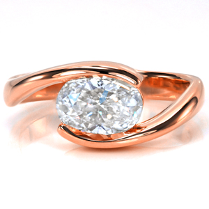 An oval set East-West adds a contemporary flair to a classic design. The elongated shape of the oval fills the open space along the top of the band perfectly. The high polish finish creates a sleek transition for the eye to focus upon the flashes of brilliance projecting from the center stone. 