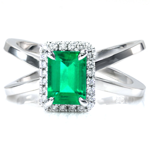 Design 3658 is shown with an emerald cut emerald gemstone center surrounded by a halo of round brilliant cut diamonds. The wide split shank design of the band is high polished to add contrast to the sparkle of the diamonds in the halo.               