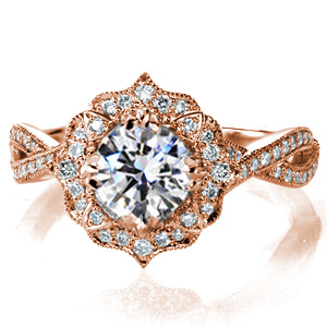A touch of regal elegance crowns the Elizabeth. This intricately detailed halo features scalloped edges and different layers of diamonds surrounding the center stone. Decorative prongs blend beautifully with the halo, while holding the center stone in place. This halo rests atop a delicately twisting diamond band. 