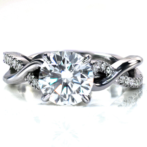 Design 3673 is a uniquely twisting split shank design featuring one band set with diamonds and one band high polished. Around the sides of the center setting small diamonds have been set for added sparkle! This design is shown here with a 1.50 carat round brilliant cut center stone. 