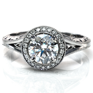 Design 3680 features a round brilliant center stone surrounded by a stunning diamond halo. There are filigree pockets visible from both the top and the sides of the ring, and the sides of the band feature bright cut hand engraving. The ring is finished with intricate milgrain detailing around the halo and on the band. 