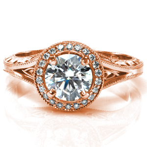 Design 3680 features a round brilliant center stone surrounded by a stunning diamond halo. There are filigree pockets visible from both the top and the sides of the ring, and the sides of the band feature bright cut hand engraving. The ring is finished with intricate milgrain detailing around the halo and on the band. 