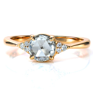 A stunning rose cut diamond is elegantly set in a reverse taper band. A cluster of three diamonds accent the 0.70 carat center stone, adding just a touch of sparkle to this antique inspired design. The highly polished band with its clean lines draw the eye into the center of this beautiful ring. 