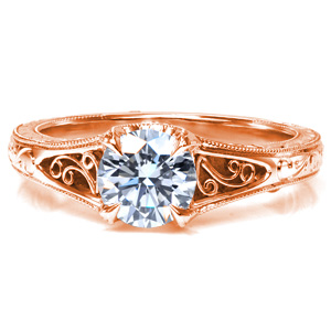 A 0.70 carat center stone is secured by uniquely designed prongs. Hand wrought filigree curls are visible from both top and side pockets, and the band features bright cut hand engraving. Milgrain texture is applied by hand to add to the antique look of this custom design.