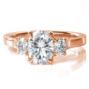 A 1.20 carat oval center stone is accented by two smaller ovals, in a classic three stone design. Each diamond sits in its own basket setting, and the three stones are cradled in a simple cathedral setting, with a highly polished band to complete the clean, elegant design.