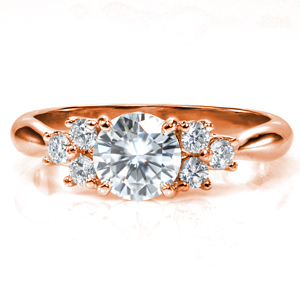 A 0.80 round brilliant center stone is accented by two clusters of three diamonds on each side. The unique lattice setting cradles the stones and blends seamlessly into the high polish reverse taper band. The beautiful curves of the band and the setting add a feminine touch to a classic design.