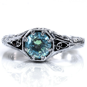 A 1.0 carat green sapphire is the centerpiece of Design 3700. Milgrain detailing is applied around the stone as well as along the band. Pockets of hand wrought filigree curls are visible from both top and side views, and the band also features intricate hand engraving. Surprise diamonds complete this custom ring.
