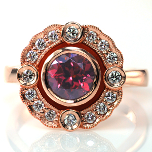 Design 3706 is a stunning Art Deco inspired engagement ring. This design features a 1.0 carat round ruby in a bezel setting in the center, which is surrounded by a scalloped halo that is edged with milgrain detail. The warmth of the rose gold is a beautiful complement to the ruby. 