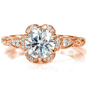 A delicate, scalloped halo adorns the dazzling center stone in Design 3720. The scalloped motif is mirrored in the band, both with  micro pavé diamonds and with intricate, relief style hand engraving and milgrain detail. A decorative basket and surprise stones complete this beautiful ring. 