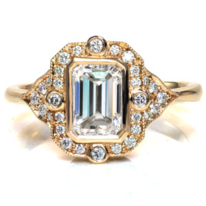 Etta features a 1 carat emerald cut diamond in a vintage inspired design. Beadset and bezel set diamonds accent the bezel set center stone, and milgrain detailing is applied by hand around the unique halo. Platinum filigree curls are formed by hand and placed into pockets under the setting, creating a two tone effect. 
