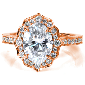 Shown with a 1.5 carat oval cut diamond, this majestic engagement ring features a scalloped halo set with mixed sizes of round brilliant cut diamonds. The cathedral style band is adorned with more sparkling round diamonds and accented with hand applied milgrain detail. 