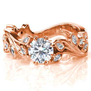Graceful curves create a stunning leaf and vine motif in Design 3744. Clusters of marquise shaped diamonds in bezel settings create sparkly leaves adorned with milgrain detail, and bezel set round brilliant diamonds add another texture. A 0.60 carat round center stone in an 8 prong setting gives the ring a focal point.