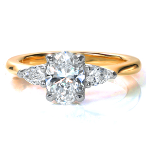 In this classic two tone design, a 0.70 carat oval diamond is featured in a clean, four prong setting. The center stone is flanked by two large pear shaped diamonds, while the 14k yellow gold band gracefully tapers into the crown, drawing the eye to the diamonds and adding warmth and contrast. 