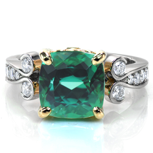 A stunning 4.5 carat, cushion cut green tourmaline takes center stage in Design 3752. The center stone is set in a custom yellow gold crown featuring a fleur-de-lis on all four sides. The high polished platinum band features large bead set diamonds and a unique flourish leading into the center setting. 